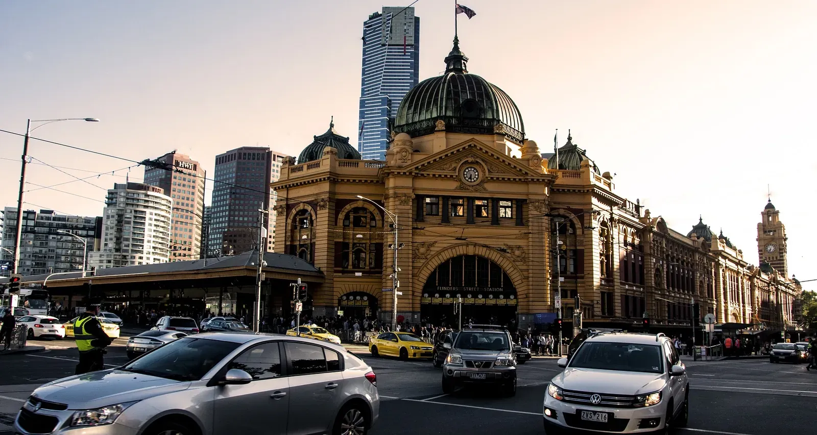 Flinders Street Station in Melbourne at dusk with traffic crossing in the foreground