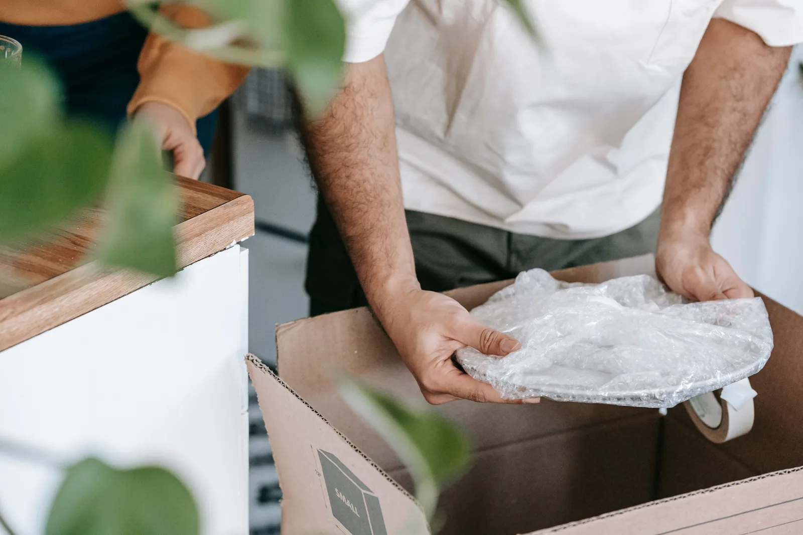 A pair of hands wrapping a dinner plate in bubble wrap before it goes into a moving box